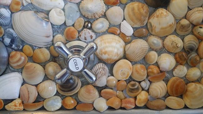 Real sea shells collected at the beach provide a colorful, durable and intriguing cover over splashback areas in the kitchen and bathroom